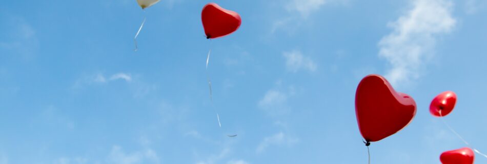 A blue sky with heart balloons floating