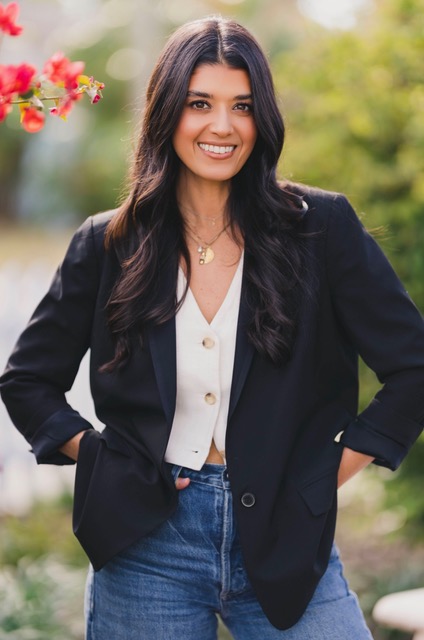 A southeast Asian woman with dark brown hair wearing a blazer and jeans. 