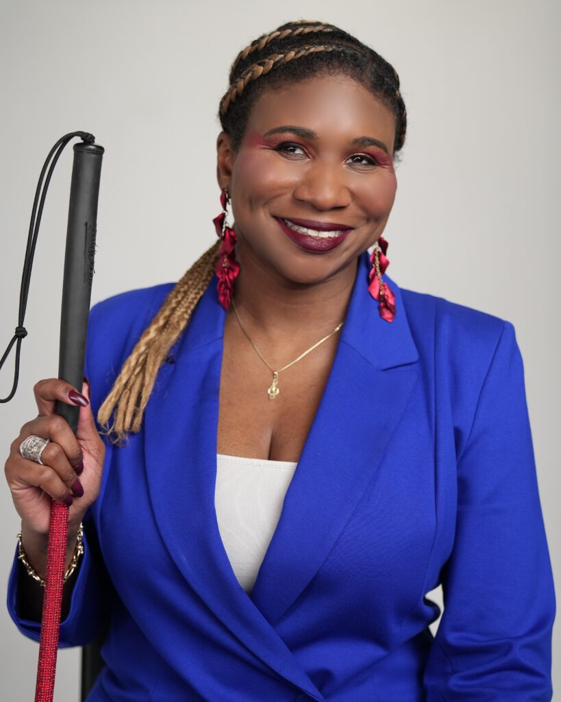 A Black female with braids and a white cane wearing a royal blue blazer.